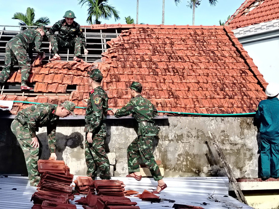 Bộ đội giúp dân lợp lại mái ngói sau bão số 13.